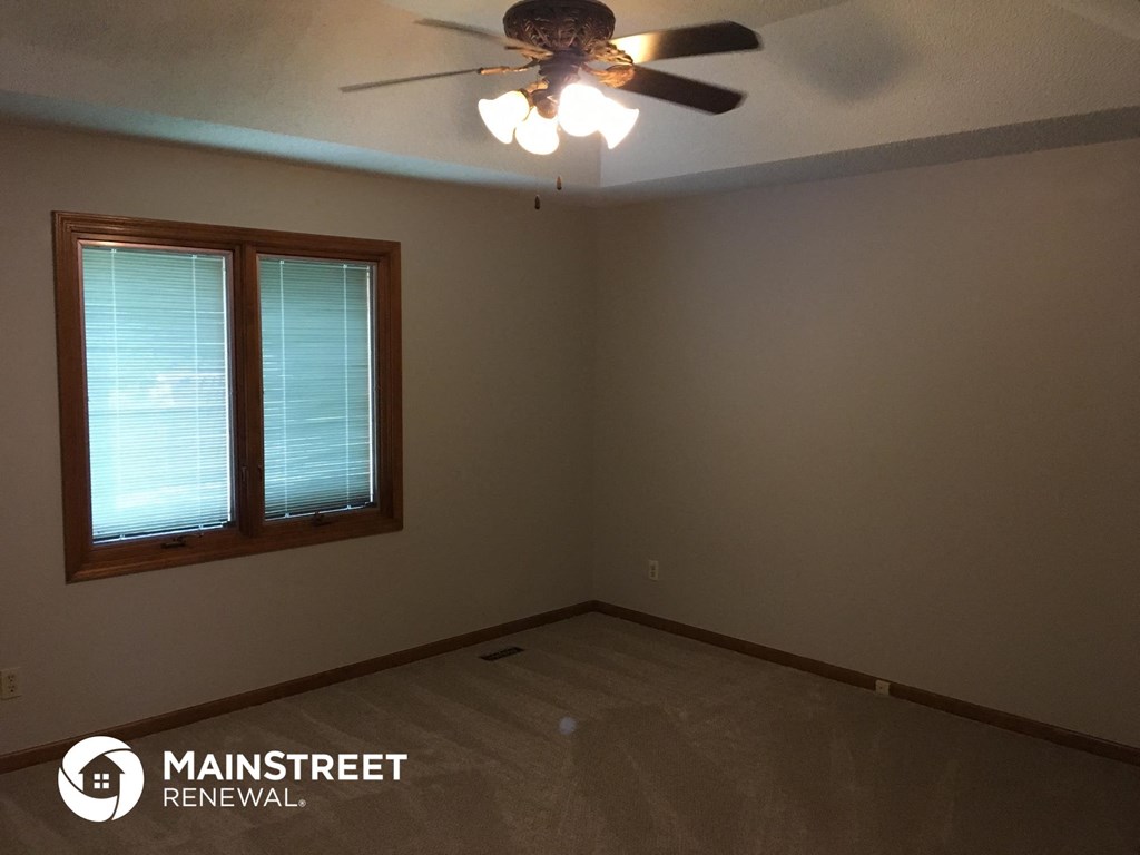 an empty room with a ceiling fan and a window