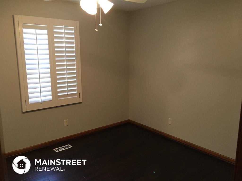the corner of a room with a window and wood floor