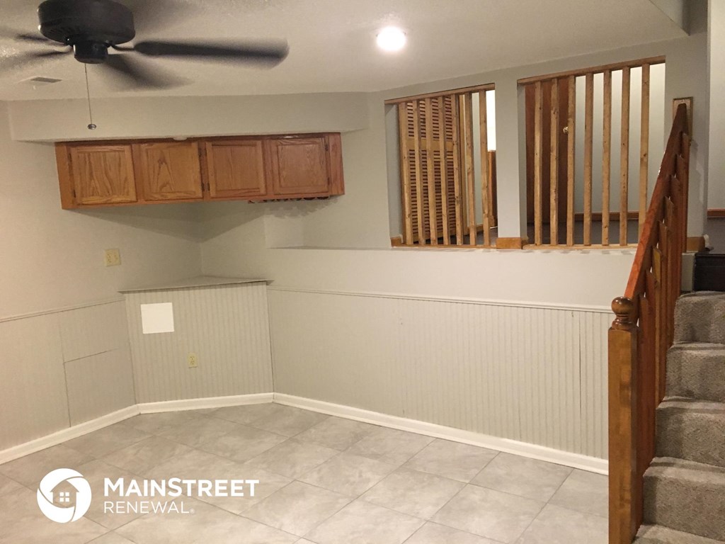 an empty basement with a staircase and a ceiling fan