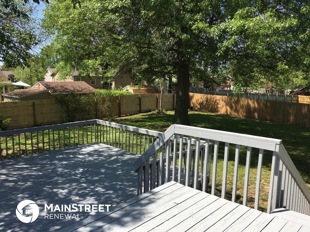 a backyard with a white deck and a tree