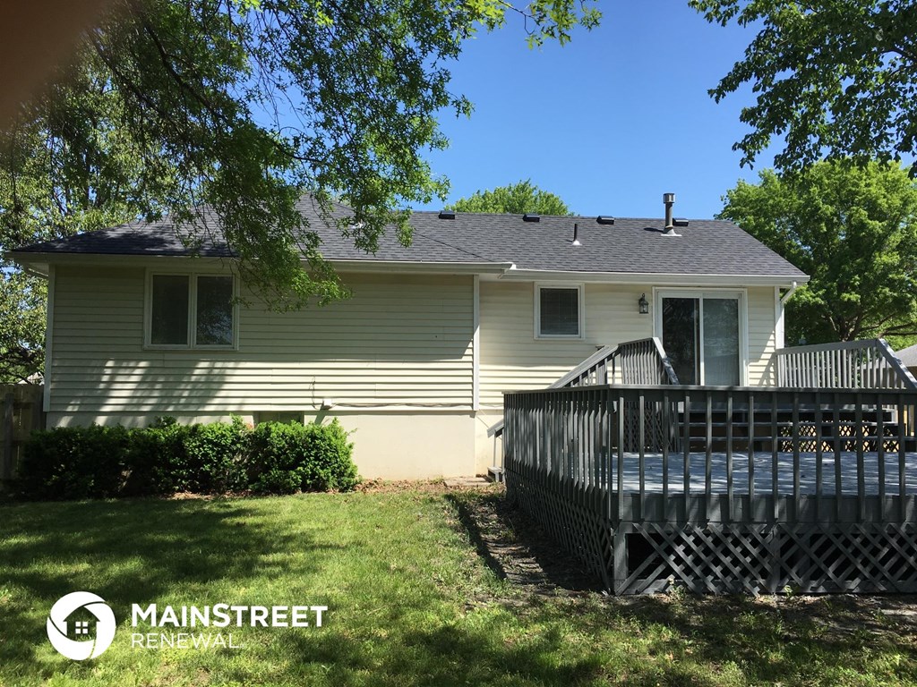 the back of a house with a deck and a wooden fence