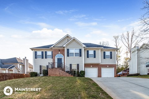 a white house with two garage doors and a lawn