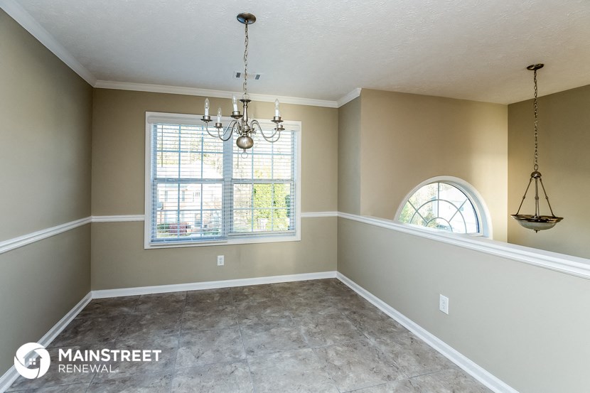 an empty dining room with a window and chandelier
