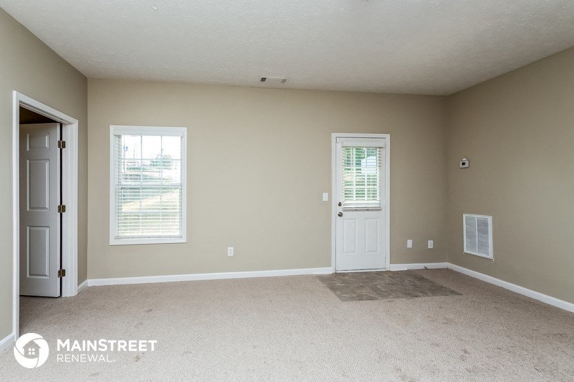 an empty room with a white door and a window