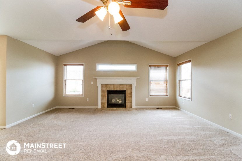 the spacious living room with fireplace and ceiling fan