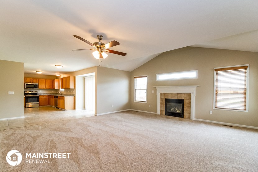 an empty living room with a fireplace and a ceiling fan
