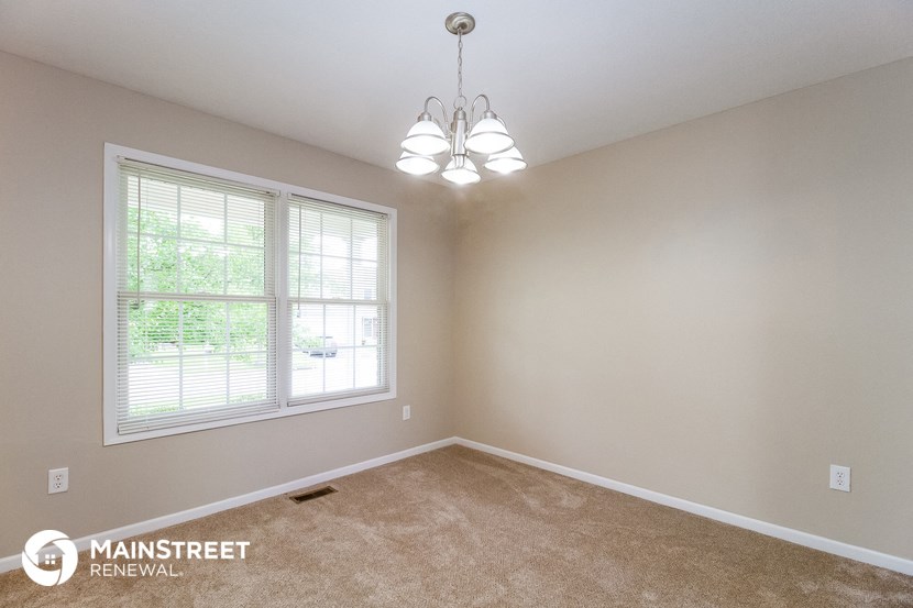 the spacious living room of a home with carpet and a chandelier