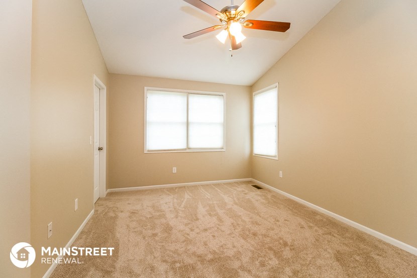the master bedroom has a carpeted floor and a ceiling fan