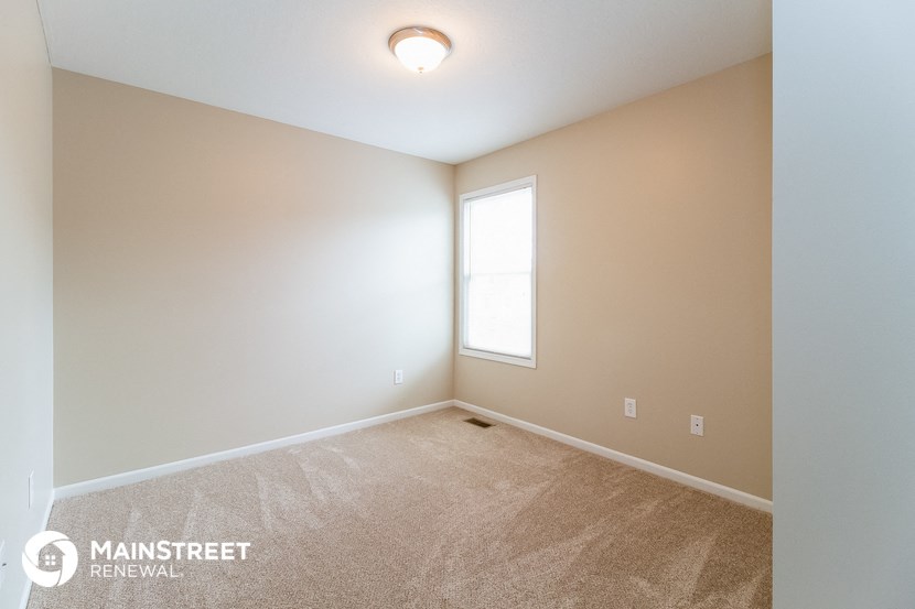 the spacious living room with carpeting and a window