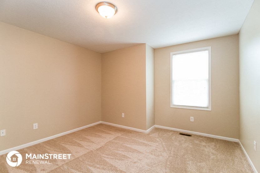 the upstairs bedroom with carpeted flooring and a window