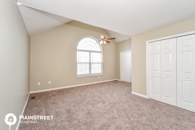 the master bedroom is spacious and has carpeted floors and a ceiling fan