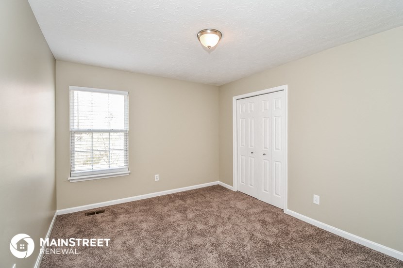 a bedroom with a carpeted floor and a white door and window