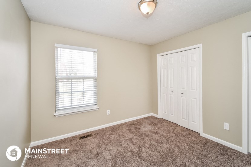 a bedroom with carpet and a white door and window