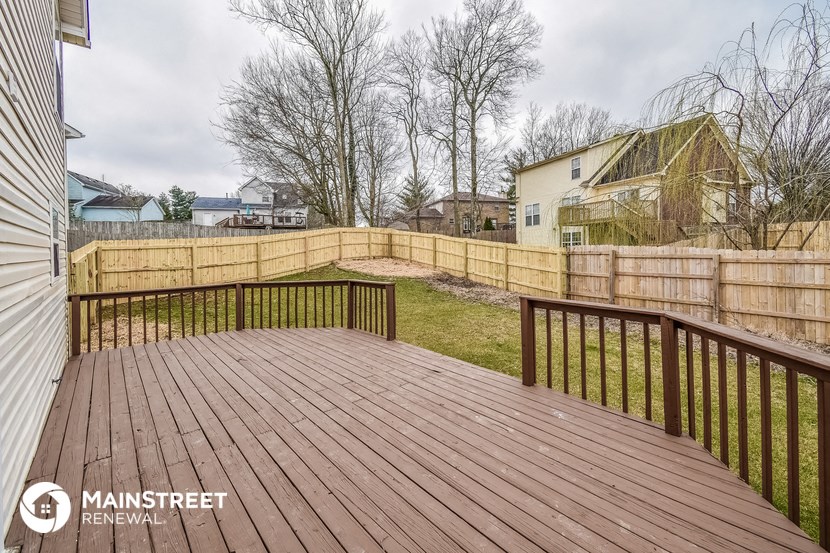 a backyard deck with a wooden fence and a yard with a house