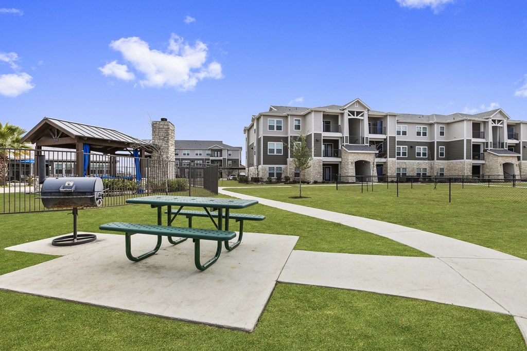 a picnic area with a table and a grill in front of an apartment building