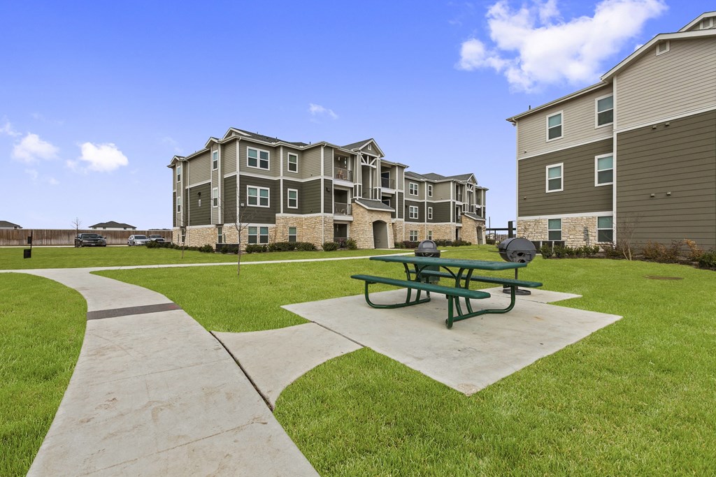 an outdoor picnic area with a green picnic table in front of an apartment building
