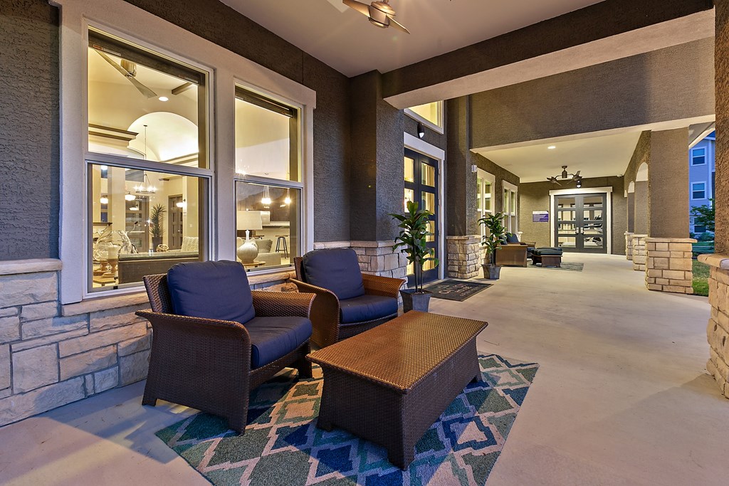 a lobby with chairs and a table in front of a building