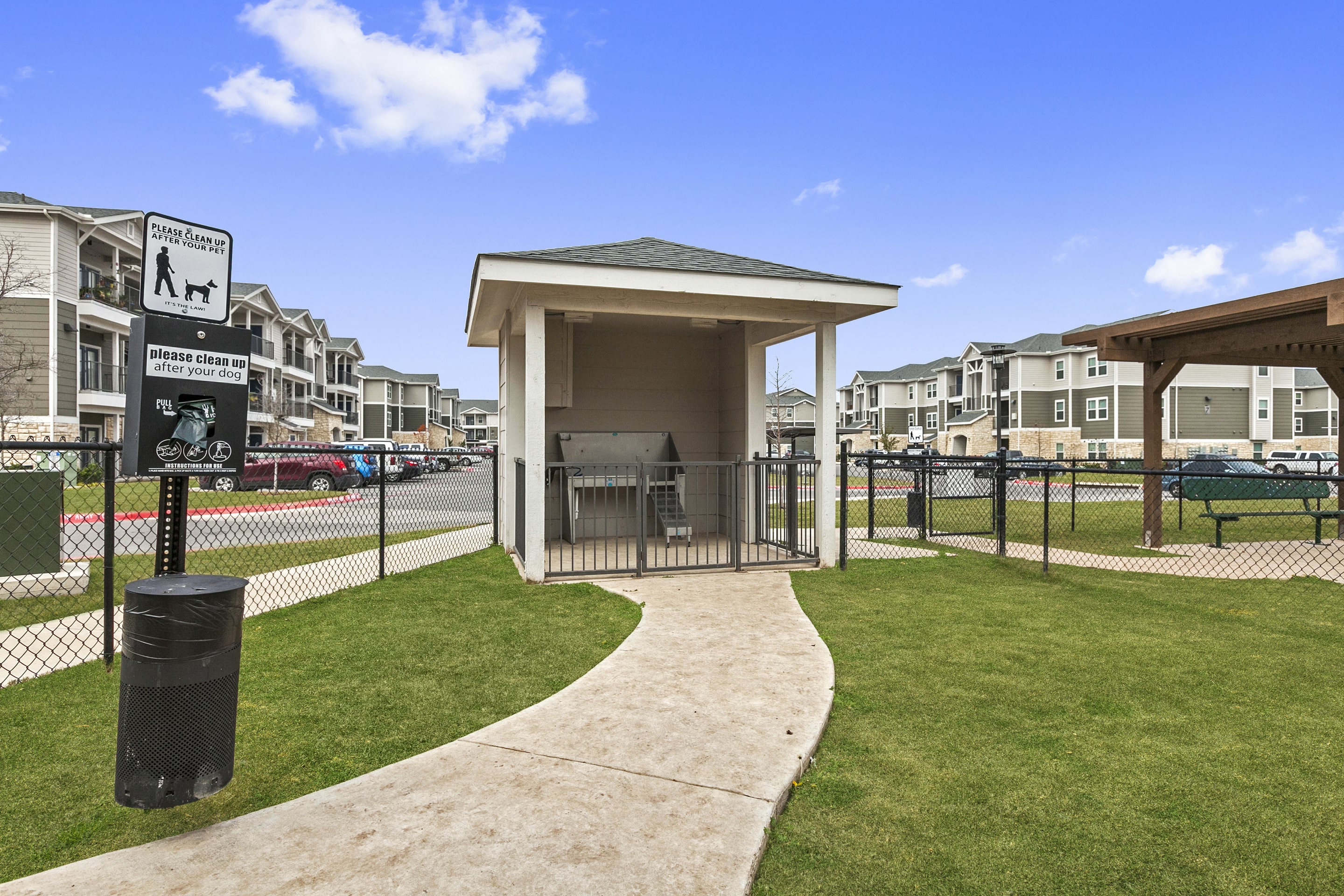 a gazebo at a dog park with apartments in the background