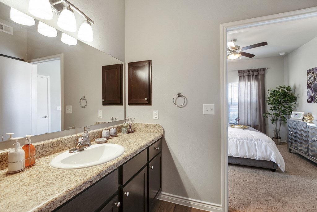 a bathroom with a sink and a mirror and a bedroom with a bed