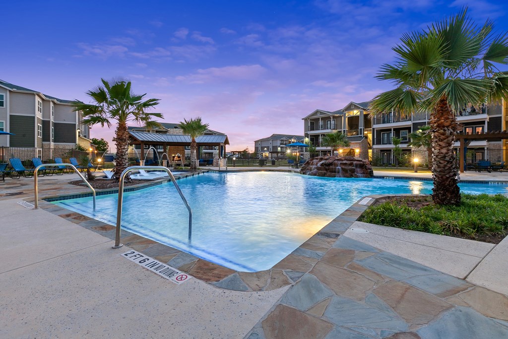 a swimming pool with palm trees and buildings in the background