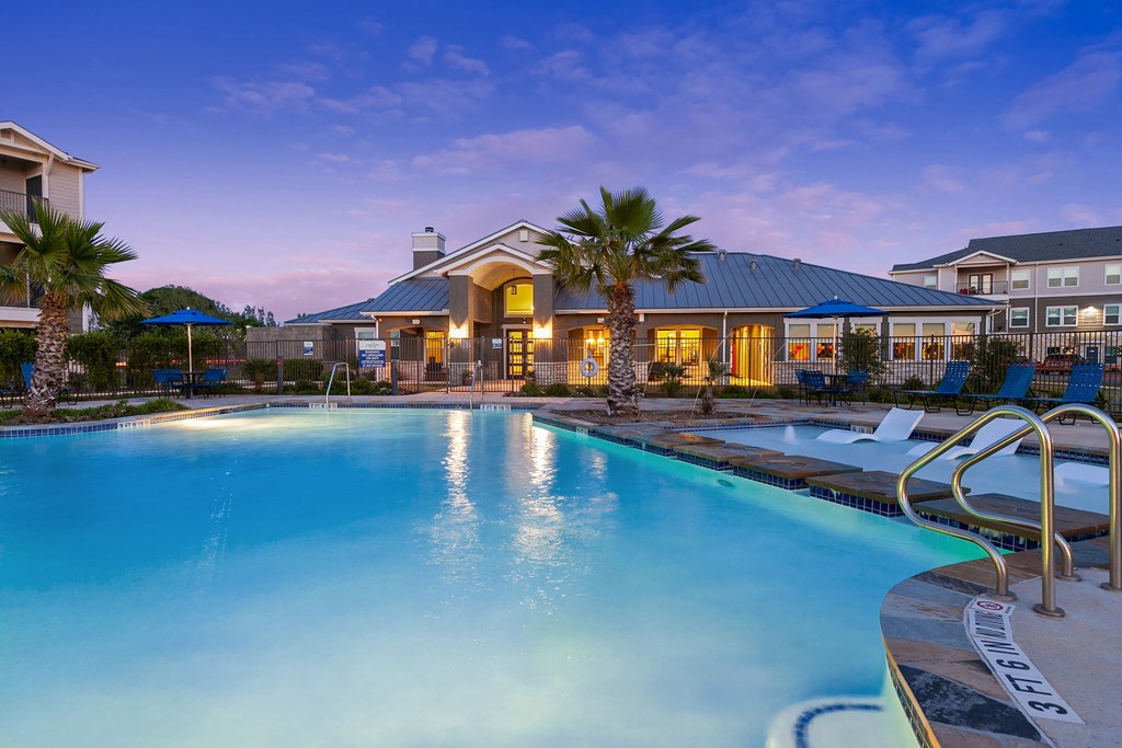 a swimming pool with chairs and a building in the background