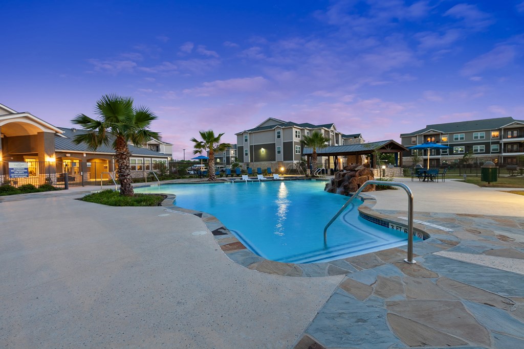 a swimming pool with palm trees and buildings in the background