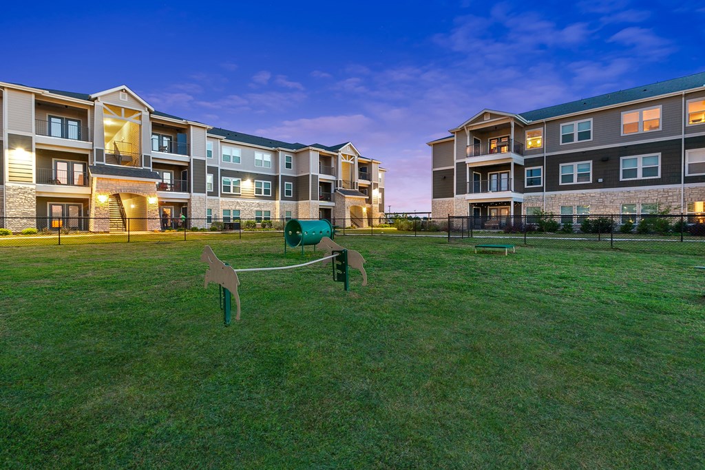 a green yard with horse statues in front of an apartment building