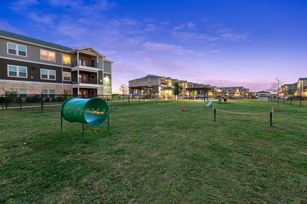 a fenced in dog park with apartments in the background