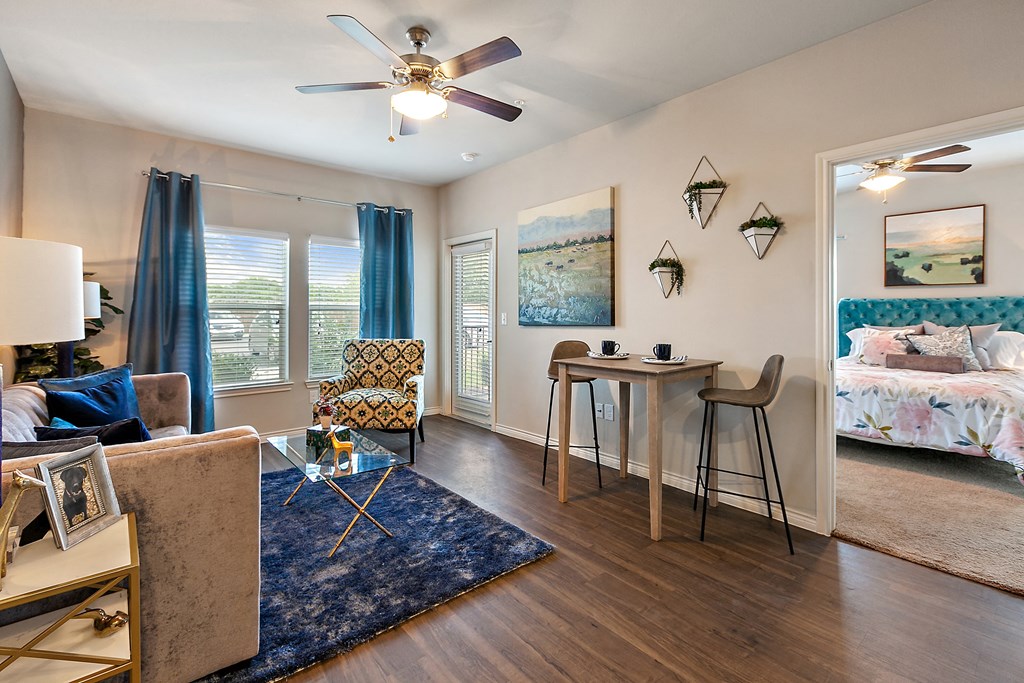 a living room with a couch and a table with a chair and a ceiling fan