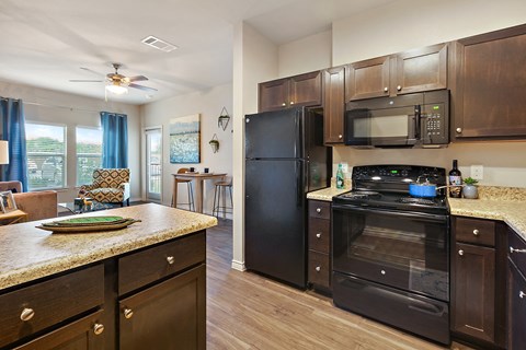 an updated kitchen with black appliances and granite counter tops