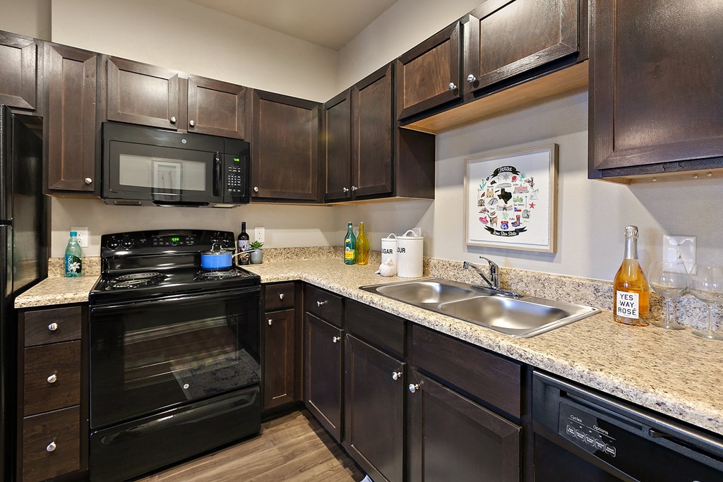 full kitchen with black appliances and granite countertops at the estates