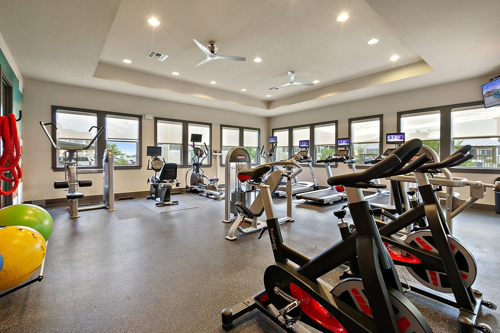 a gym with lots of exercise equipment and windows