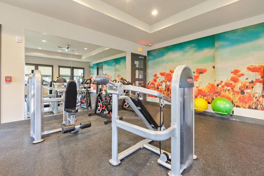 a gym with exercise equipment and a mural of flowers