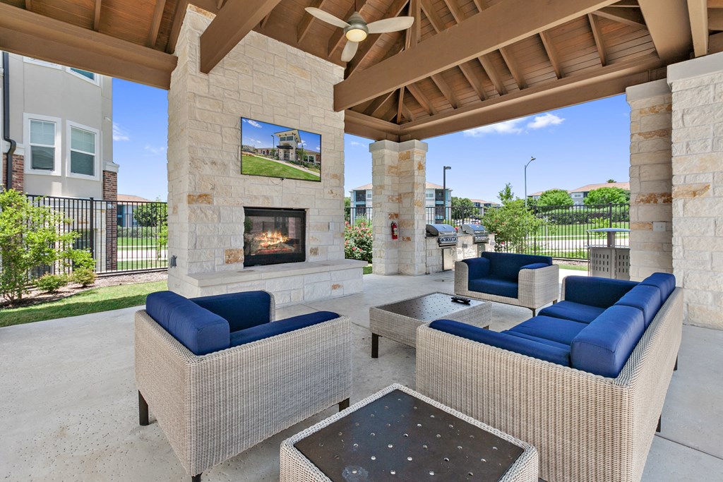 One-Bedroom Apartments in San Marcos, TX - Sadler House Apartments - Pavilion For Outdoor Entertainment with a Large Fire Place, Comfy Outdoor Couches, Large Flat Screen TV, Shaded Overhang, Ceiling Fan, and Shared BBQs