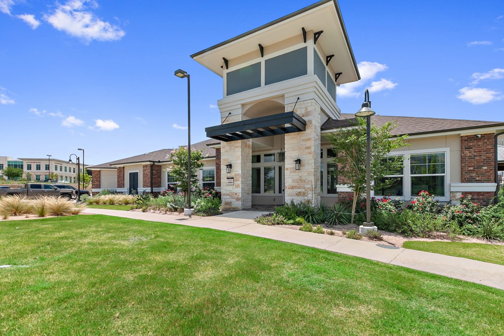the front of a building with a walkway and grass
