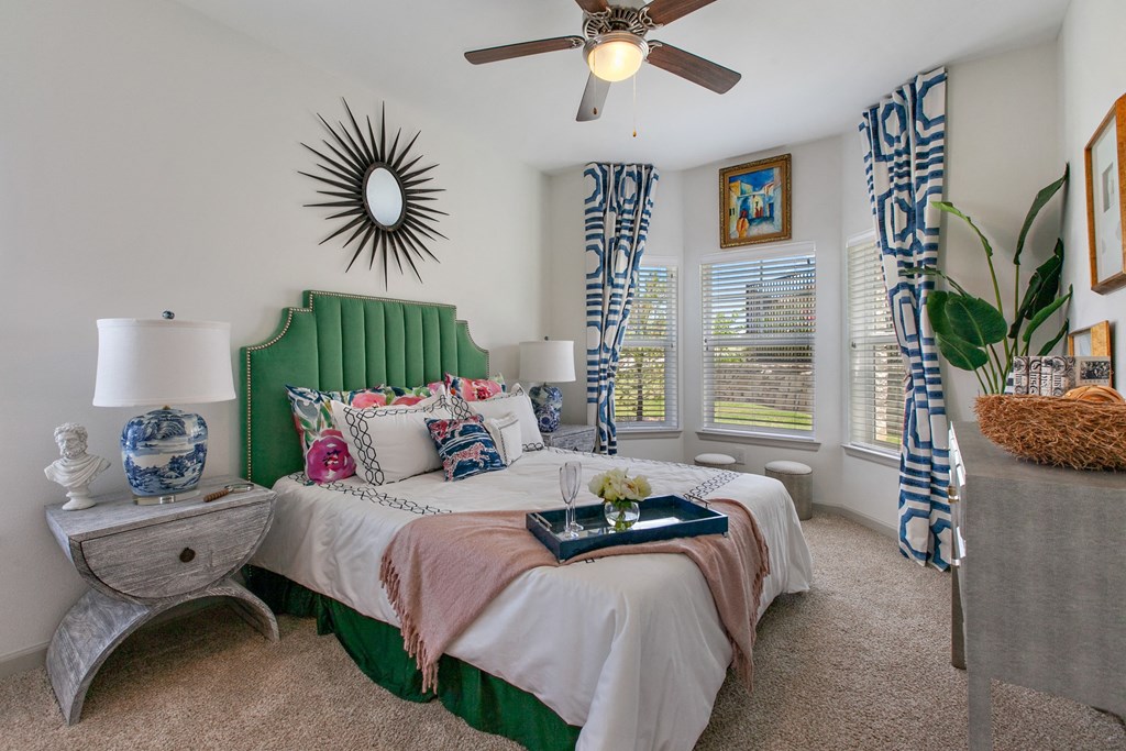 Apartments for Rent in San Marcos, TX - Sadler House Apartments - Spacious Bedroom with High Ceilings, a Ceiling Fan, Plush Carpet Flooring, and Bay-Style Windows with Blinds