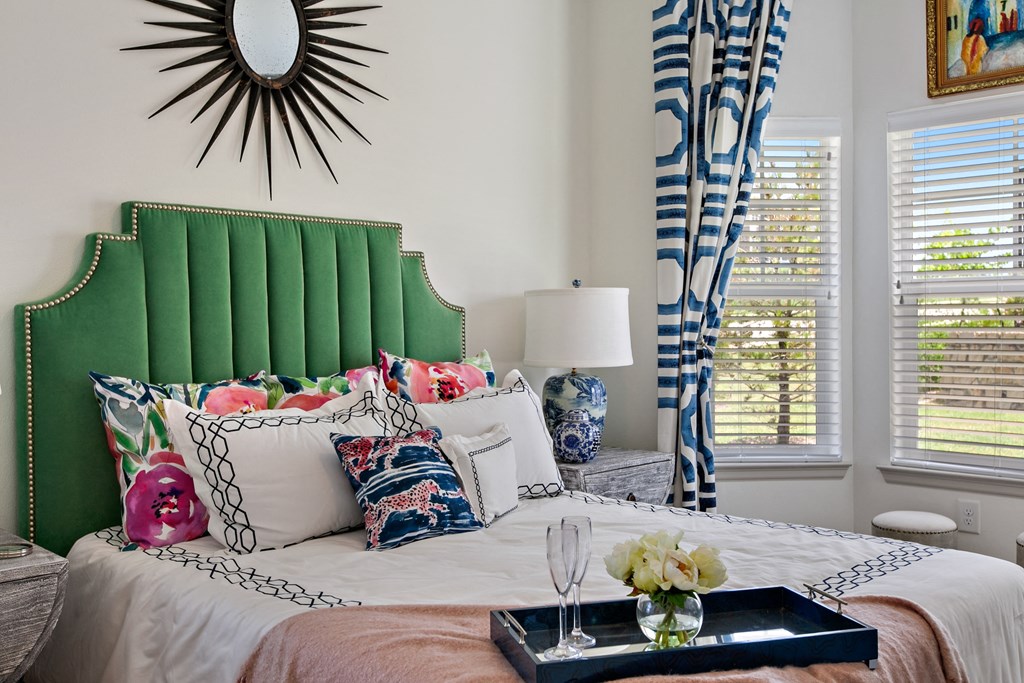 Two-Bedroom Apartments in San Marcos, TX-Sadler House-Bedroom-Green Headboard, Large Windows, Blue Drapes, Wall-to-Wall Carpet, and Grey Night Stand