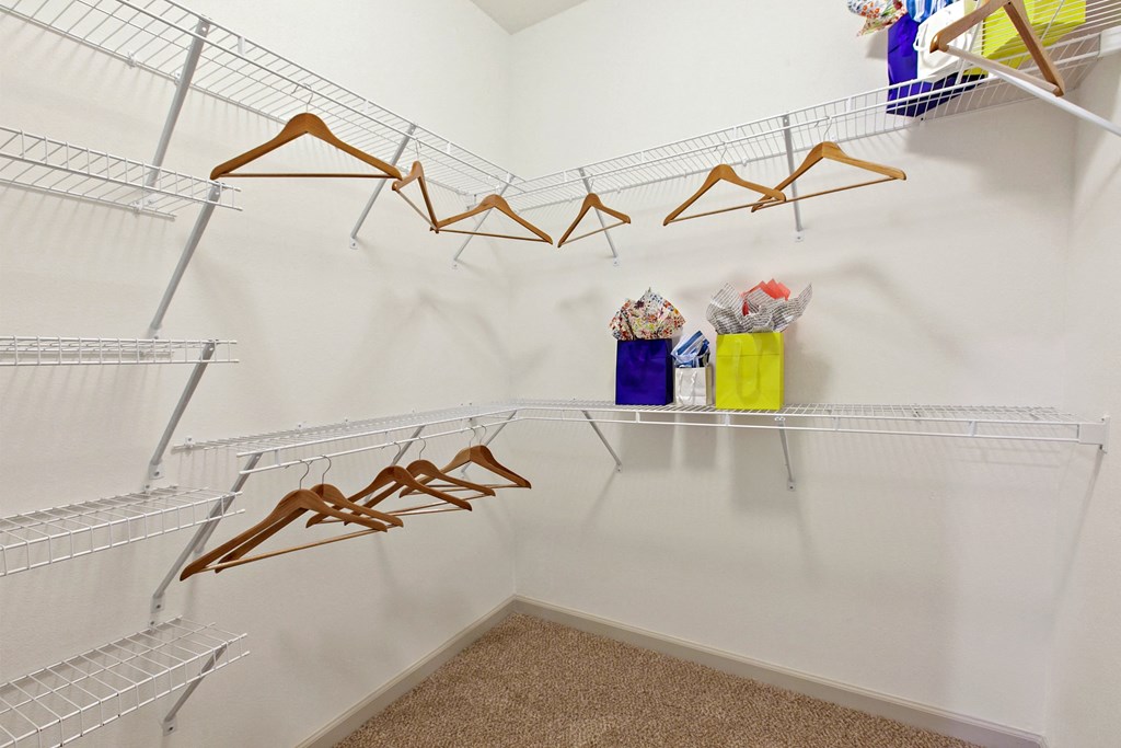 a walk in closet with wire shelves and clothes racks