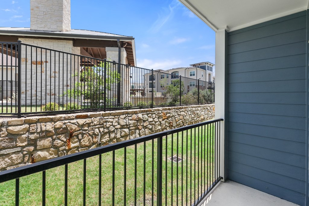 the view from the balcony of a house with a stone wall and a metal fence