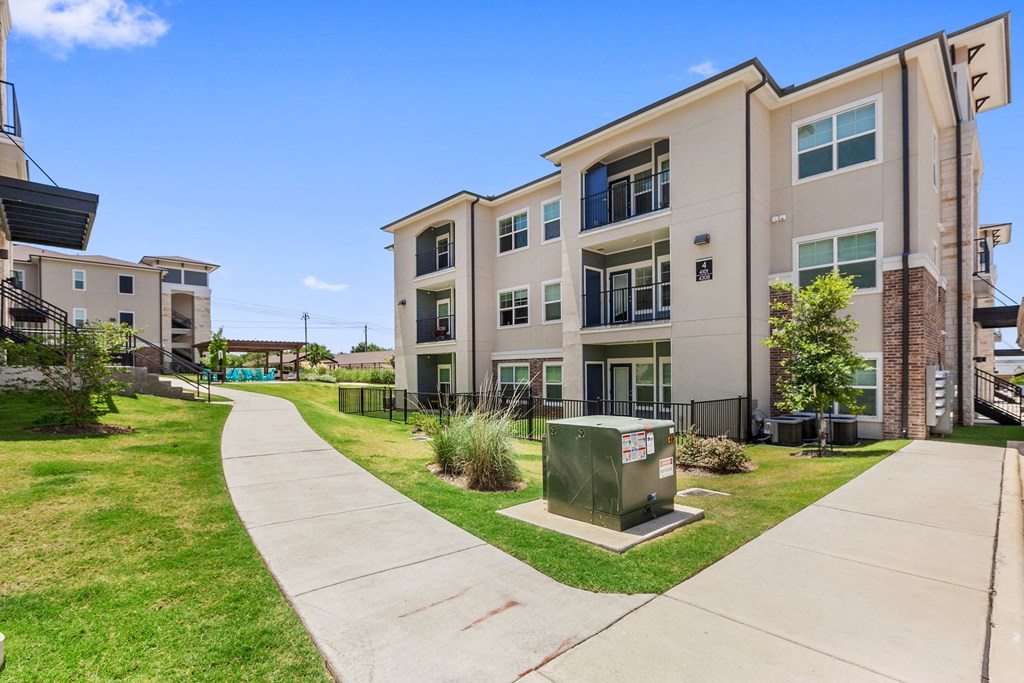 a sidewalk leading to an apartment building with a green mailbox