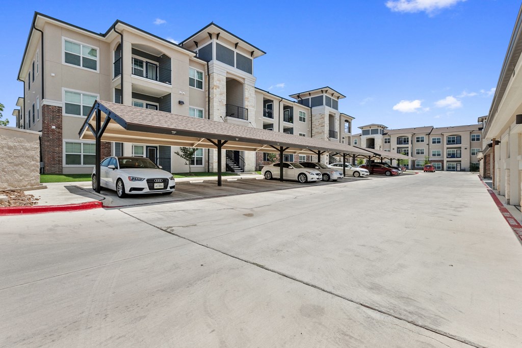 an empty parking lot with cars in front of an apartment building