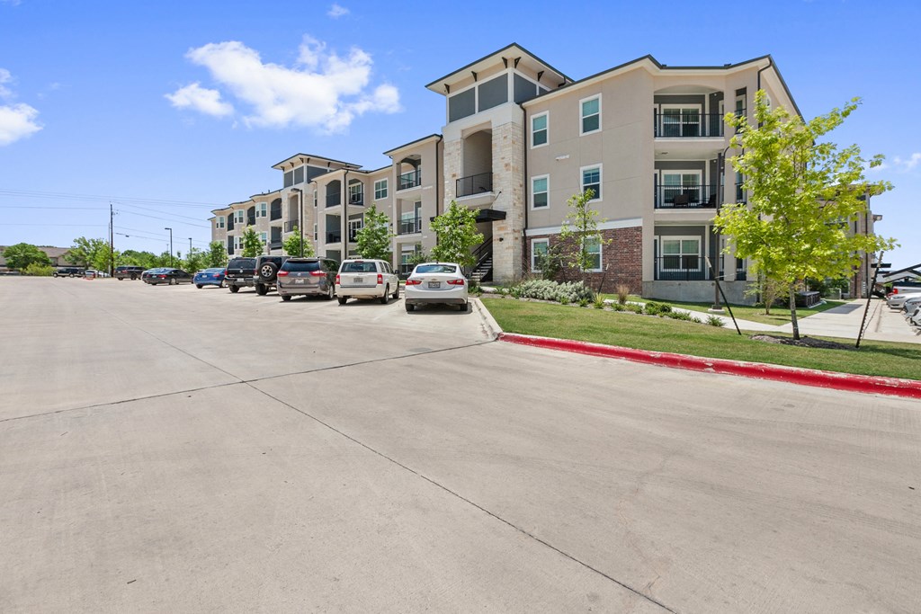 a row of apartment buildings with cars parked on the street
