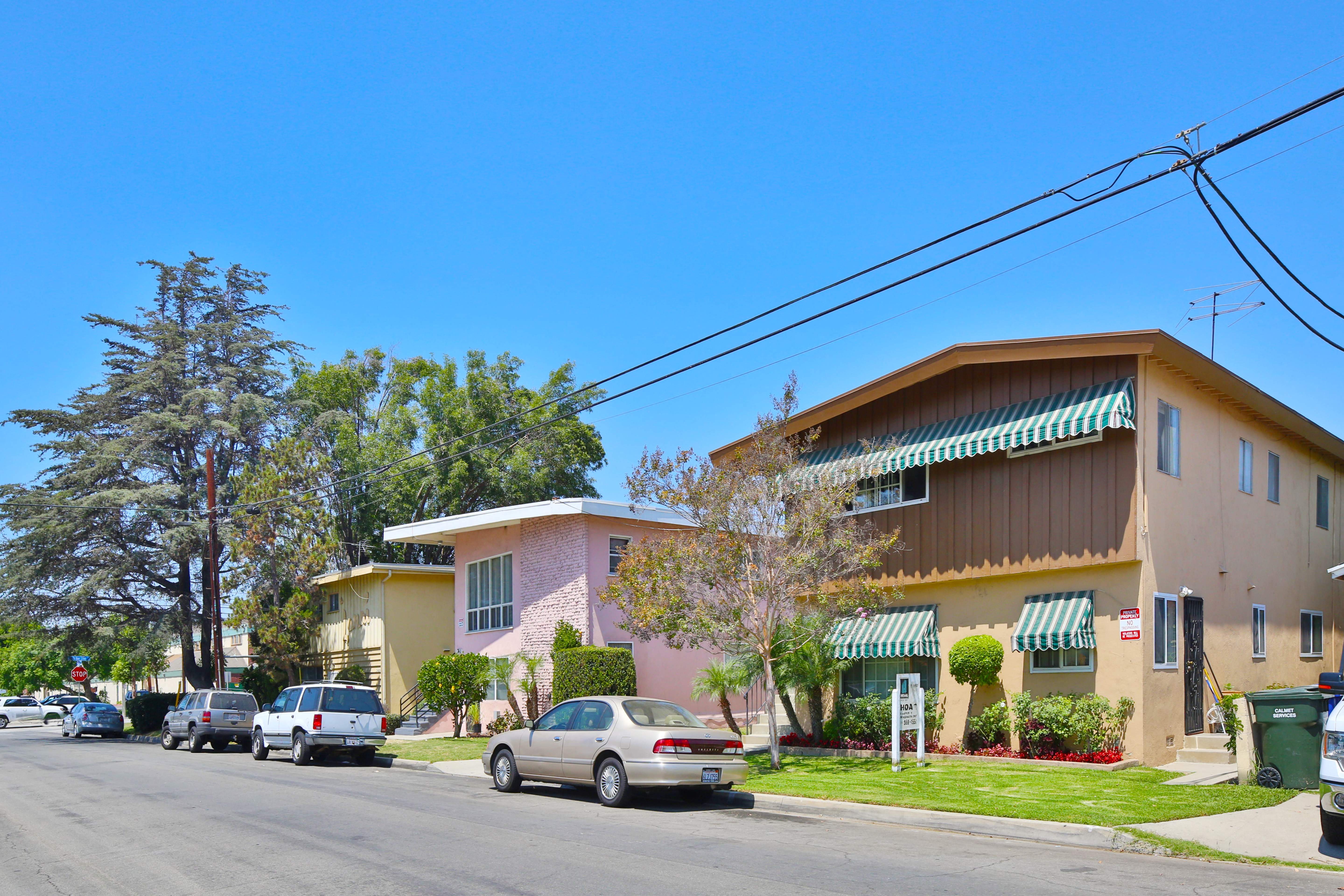 A row of houses with cars parked in front.