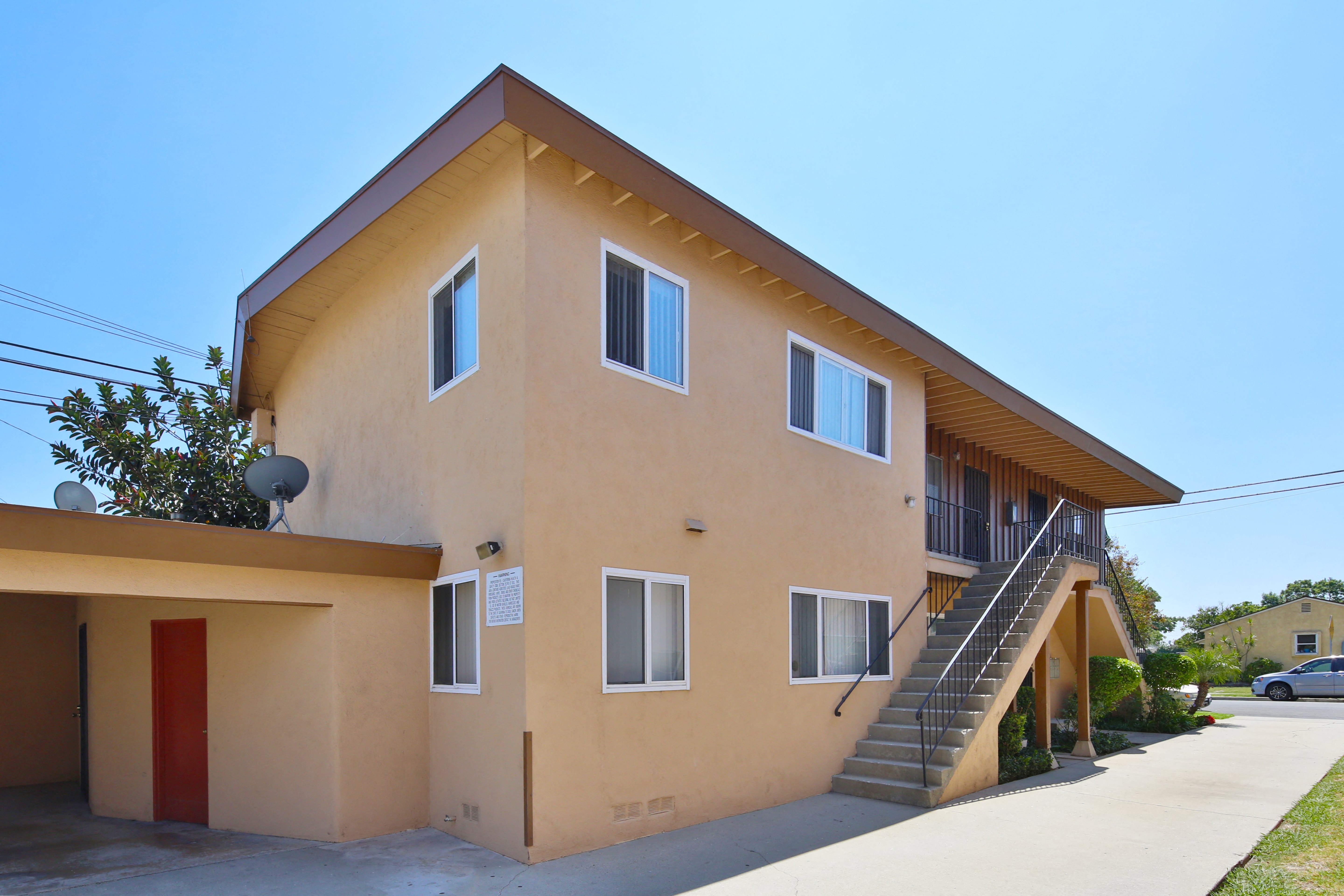 A two-story building with a red door and a staircase leading to the second floor.