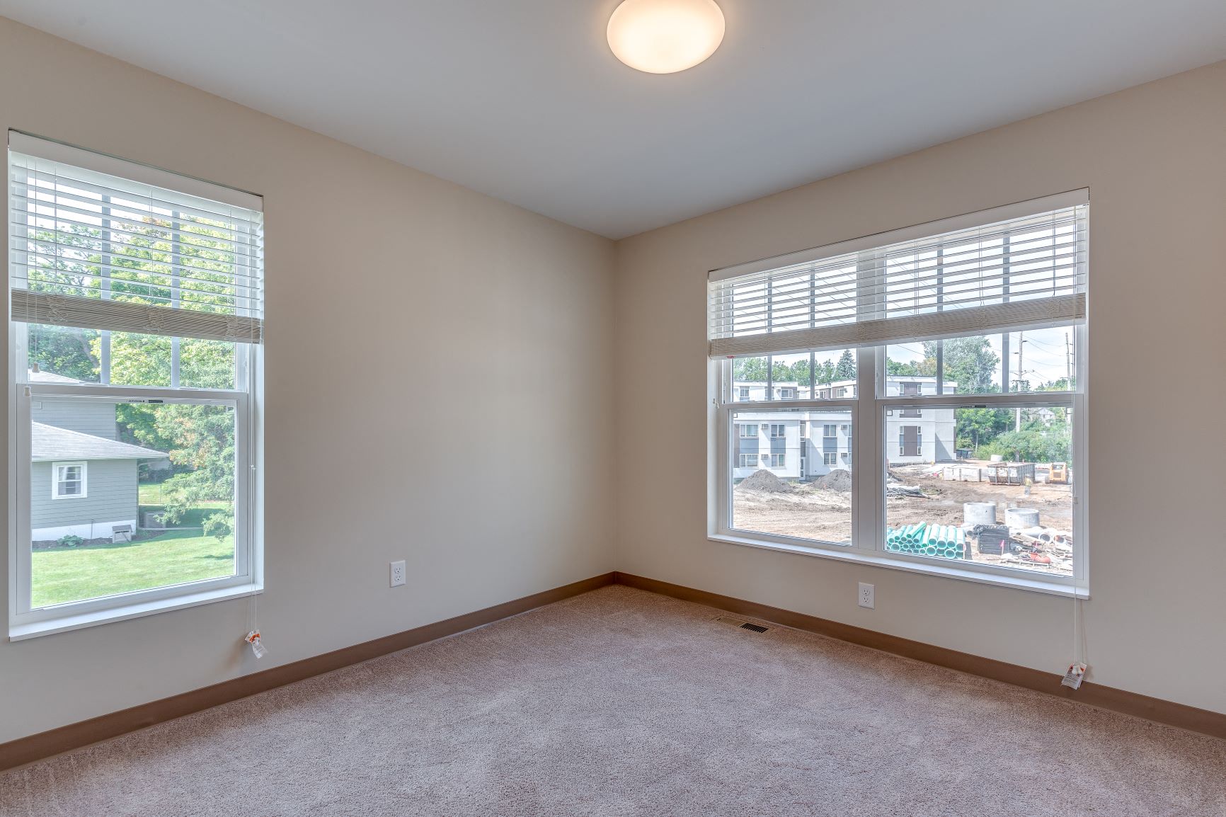 a bedroom with two large windows and a carpeted floor