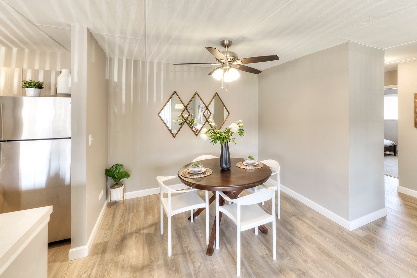 A dining room with a table set for two and a ceiling fan.