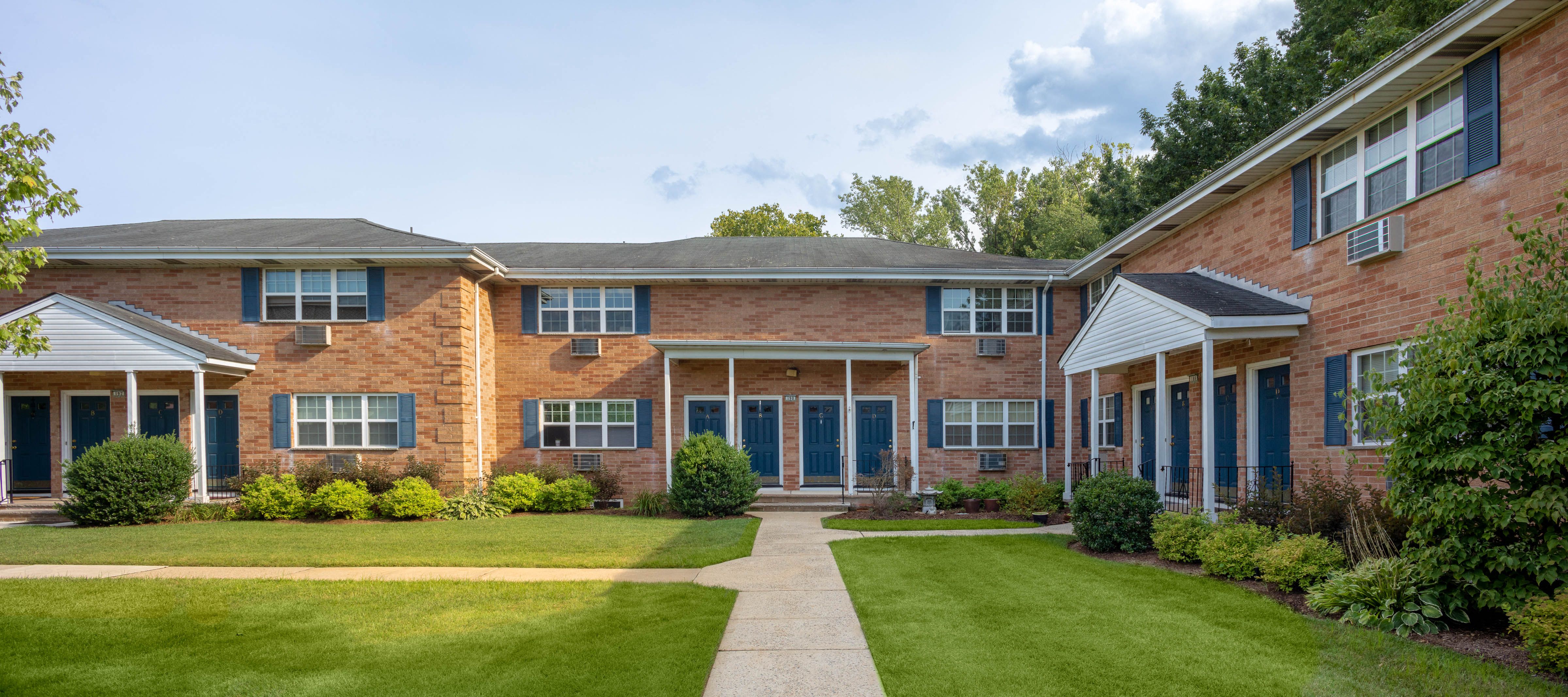 a brick building with a green lawn and a sidewalk