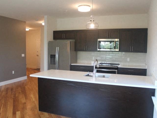an empty kitchen with a white counter top