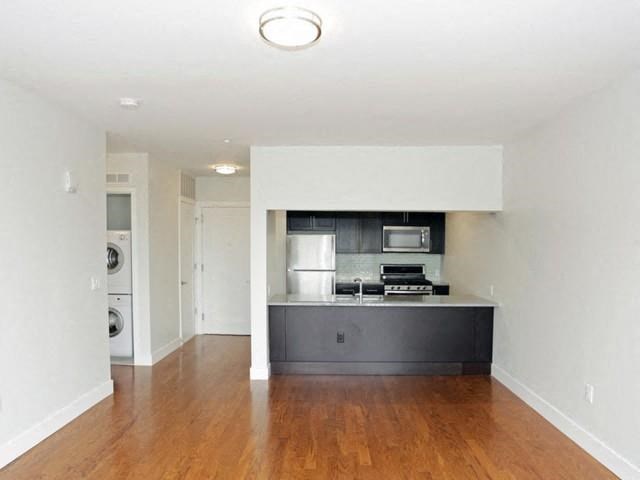 an empty living room and kitchen with a wood floor