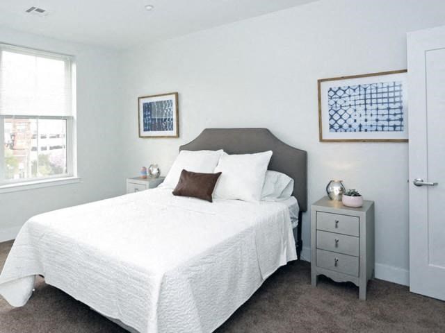a white bedroom with a bed and a night stand